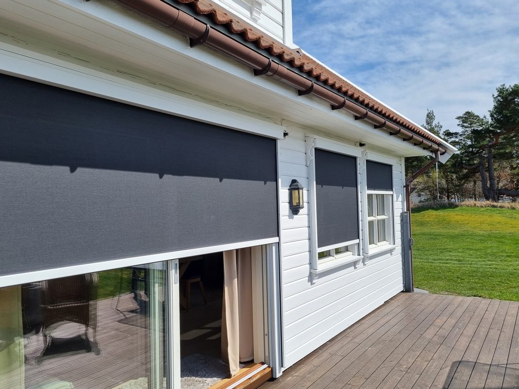 Eksteriørbilde av terrassen til en enebolig med skyvedør som er dekket av en zipscreen.